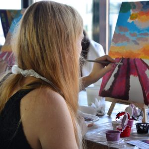 woman painting at an easel during a paint party